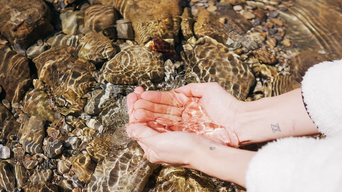 a person holding their hands in a stream of water